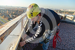 Industrial climber ties a rope on the roof of a building