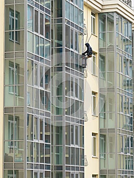 Industrial climber wash the windows of modern building. Concept of urban works