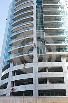 Industrial climber wash the windows of modern skyscraper. Dubai UAE.