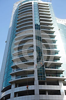 Industrial climber wash the windows of modern skyscraper. Dubai UAE.