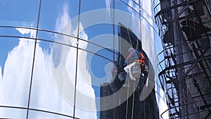 Industrial climber wash windows of skyscraper. Window washers on glass building facade. Professions