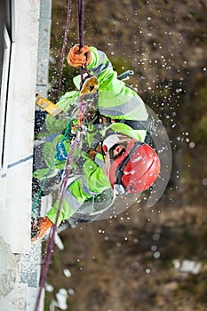 Industrial climber during winterization works, styrofoam dust falling down