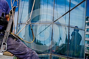 Industrial climber at work, cleaning facade of a modern office b