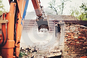 industrial excavator using scoop for demolishing old house and ruins photo