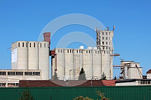 Industrial complex multiple tall concrete storage silos with cell phone antennas and transmitters on top surrounded with dark