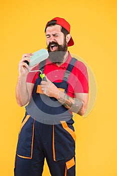 Industrial concept. creative repair concept. bearded man singing in roller tool. hipster builder in cap yellow