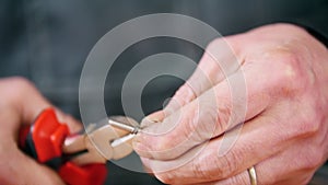 Industrial concept. A man worker holding a small skrew and twists it. Cutting the wire with a nippers