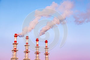 Industrial concept. Smoking chimneys or factory pipes against the blue twilight sky