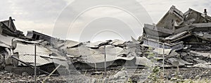 Industrial concrete building destructed by strike. Disaster scene full of debris, dust and crashed buildings