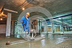 Concrete floor construction. Worker with screeder photo