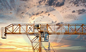 Industrial construction cranes and building silhouettes over sun at sunrise