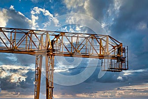 Industrial construction cranes and building silhouettes over sun at sunrise