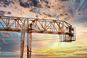 Industrial construction cranes and building silhouettes over sun at sunrise