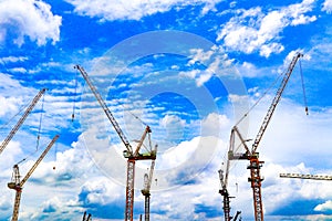 Industrial construction cranes and condominium building on the blue sky