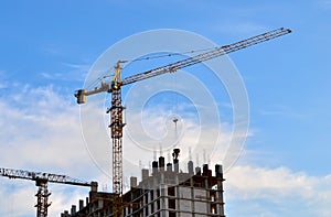Industrial construction cranes and silhouettes of workers during installation of formwork