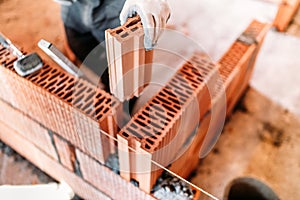 construction worker using spatula and trowel for building walls with bricks and mortar