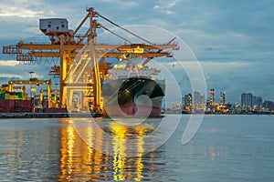 Industrial Container Cargo freight ship with working crane bridge in shipyard at dusk for Logistic Import Export background