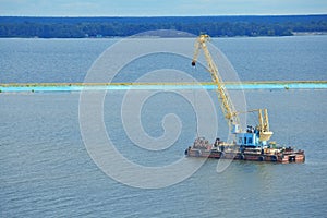Industrial crane ship loading cargo, working on water