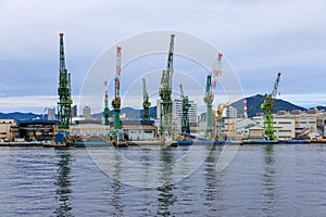 Industrial cranes at cargo loading dock at quiet harbor on cloudy day