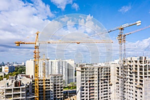 Industrial cranes at construction site against blue sky background. development of new residential area