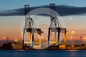 Industrial cranes in a port at sunset