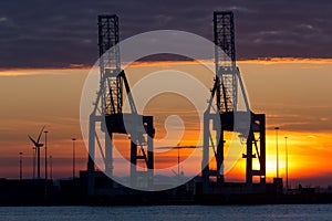 Industrial cranes in a port at sunset