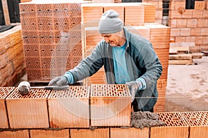 Construction bricklayer worker building walls with bricks, mortar and putty knife