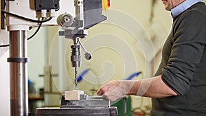 Industrial drilling machine - a man worker makes holes in metal plate