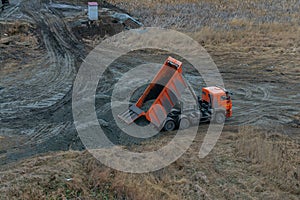 Industrial dumper truck working on highway construction site, loading and unloading gravel and earth