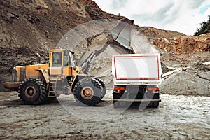 Industrial dumper trucks and wheel loader bulldozer working on highway construction site, loading and unloading gravel and earth m