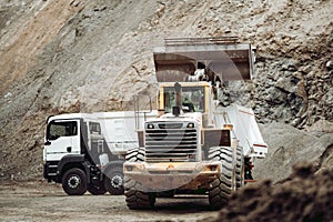 Industrial dumper trucks and wheel loader working on construction site, loading and unloading gravel and earth. heavy duty machine