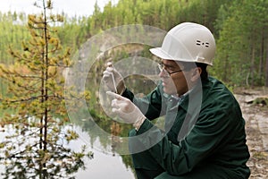 Industrial ecologist takes a sample of water from a flooded quarry