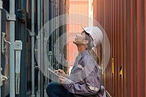 Industrial engineer checking containers with digital tablet in logistic shipping cargo yard. Asian female worker in uniform with