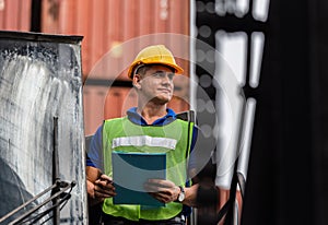 Industrial engineer in hard hat control loading containers box on stacker lifting cargo container, Dock worker man with clipboard