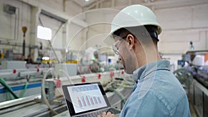 Industrial Engineer in Hard Hat Uses Laptop. He Works at the Heavy Industry Manufacturing Factory.