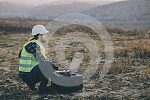 Industrial Engineer in Hard Hat Wearing Safety Jacket Uses Touchscreen Laptop. He Works at the Heavy Industry