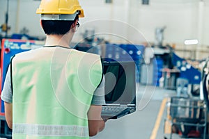 Industrial engineer with hard hat working with laptop at factory