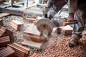 Industrial engineer working on cutting bricks at construction site, using a grinder, electrical mitre saw with sharp blade