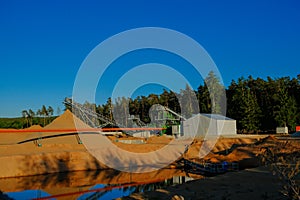 Industrial equipment for sand mining.Equipment for extracting sand is situated on the shore of a pond with, surrounded