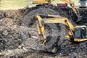 industrial excavator digging into trash at urban dumping grounds