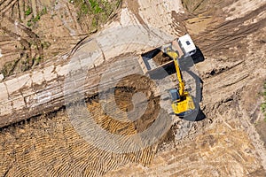 Industrial excavator loading ground into a dump truck on construction site. aerial view
