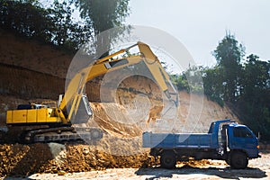 Industrial excavator and truck working on construction site