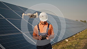 Industrial expert wearing helmet and controlling drone in photovoltaic solar power plant. Solar panel array installation