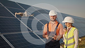 Industrial expert wearing helmet and controlling drone in photovoltaic solar power plant. Solar panel array installation