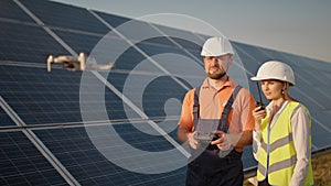 Industrial expert wearing helmet and controlling drone in photovoltaic solar power plant. Solar panel array installation