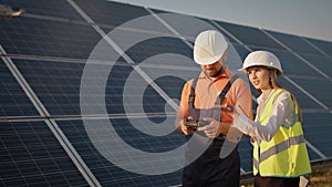 Industrial expert wearing helmet and controlling drone in photovoltaic solar power plant. Solar panel array installation