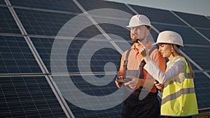 Industrial expert wearing helmet and controlling drone in photovoltaic solar power plant. Solar panel array installation