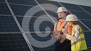 Industrial expert wearing helmet and controlling drone in photovoltaic solar power plant. Solar panel array installation