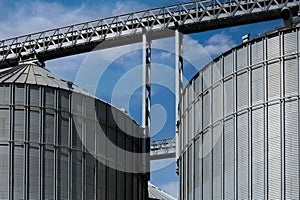 Industrial facilities of feed and flour mills. Close-up of steel grain storage silos with conical bottom, can be used for various photo