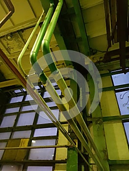 Industrial facility. Three metal curved tubes. The lighting of the building with a green tint